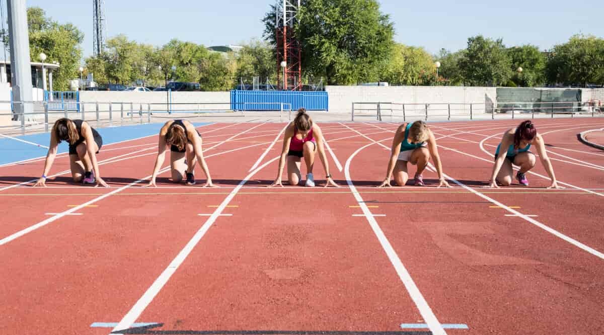 Sportlerinnen befinden sich in der Startposition auf einer Tartarnbahn