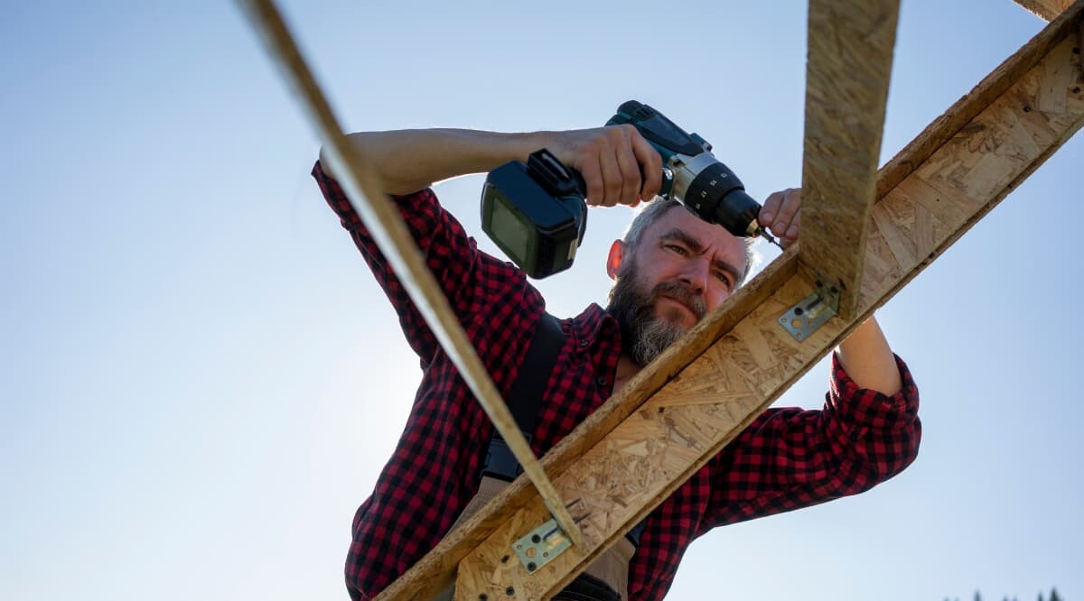 Handwerker bohrt Holzbrett mit Elektrowerkzeug 