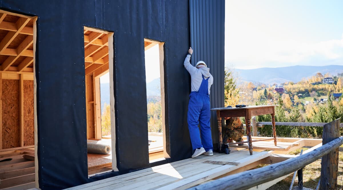 Bauarbeiter bringt Wellblech als Fassade des künftigen Hauses an